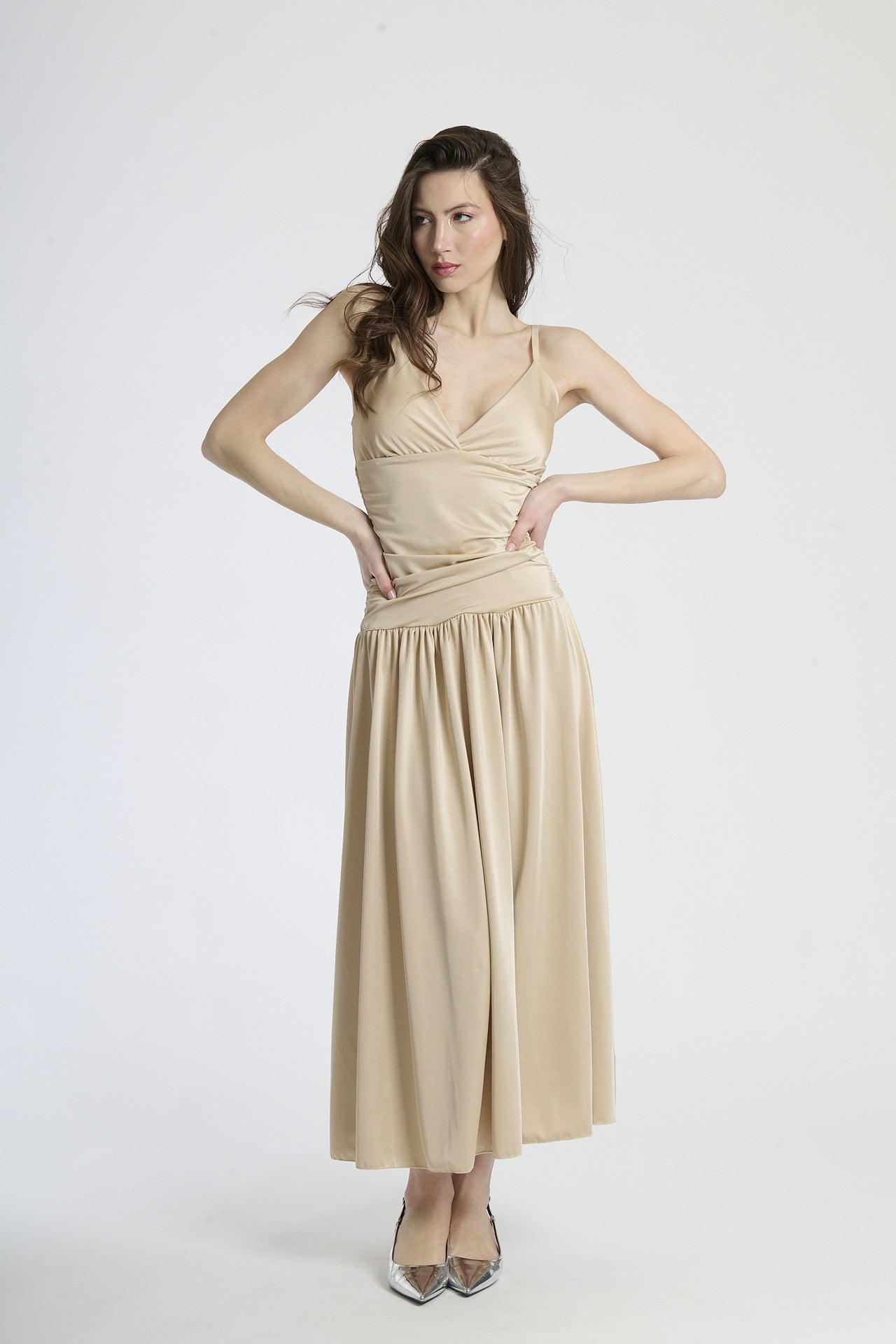 Abito lungo beige con scollatura a V profonda, silhouette dritta e gonna fluttuante.
