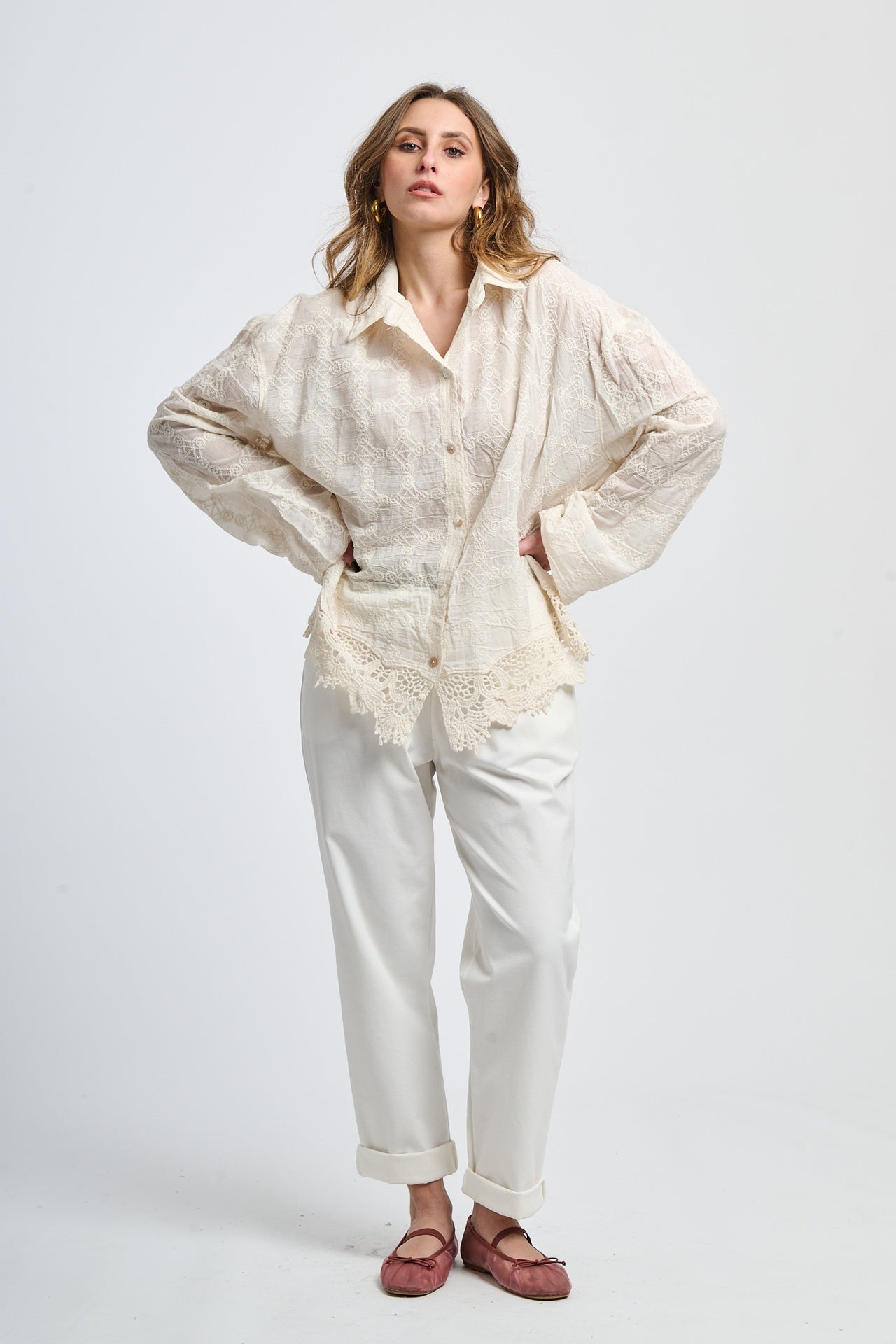 Look con maglia rosa scura e pantaloni grigi slim, accessoriato con una cintura nera, eleganza contemporanea.