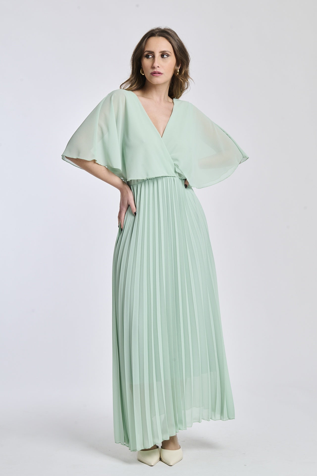 Un abito in salvia con lo stesso design crociato e maniche a mantello, creando un'atmosfera di tranquillità e armonia.