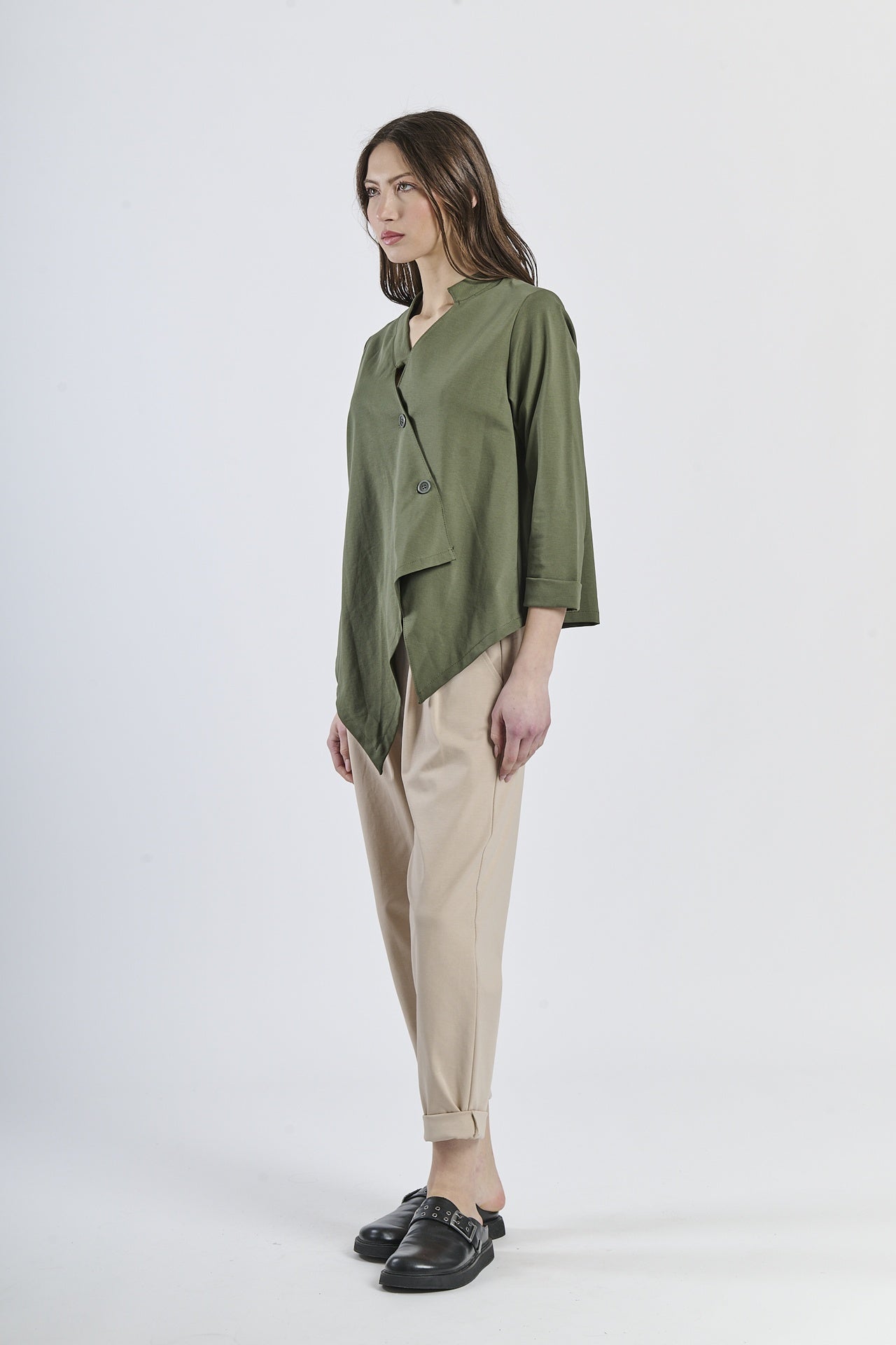 Look con camicia verde a taglio asimmetrico, pantaloni beige a gamba larga e mocassini marroni