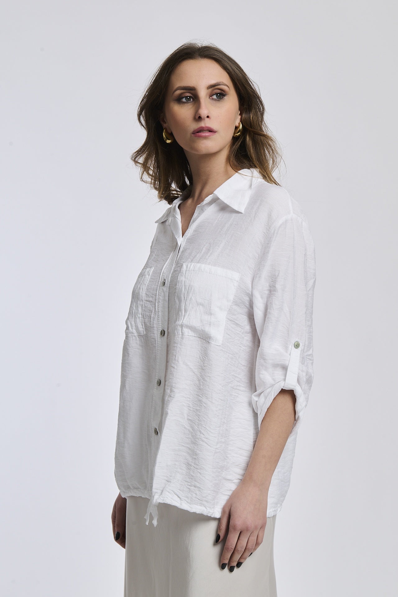Donna con camicia bianca di cotone, maniche arrotolate, perfetta per un ambiente lavorativo o casual.