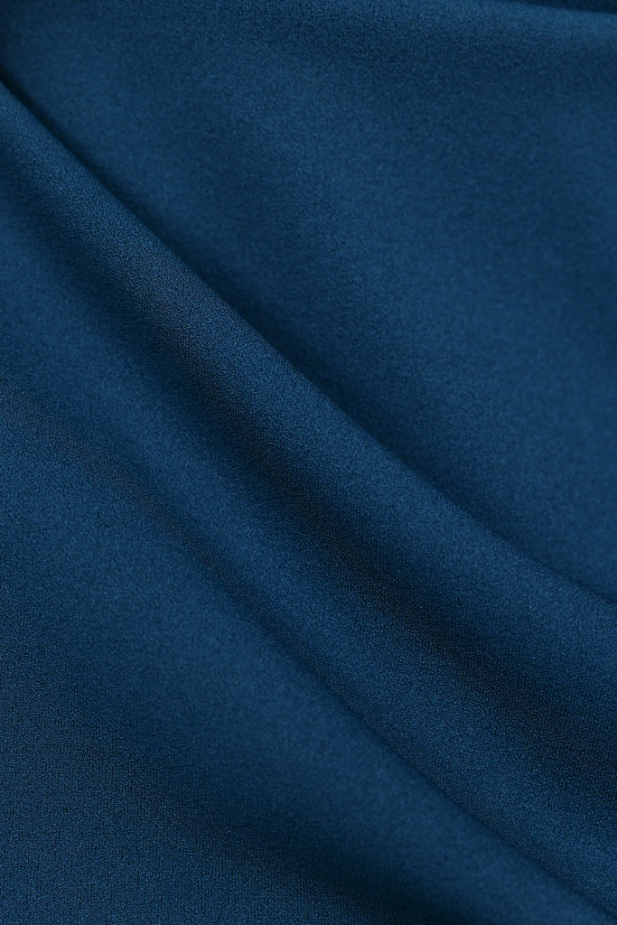 Donna indossa un abito ottanio senza maniche, lunghezza midi,