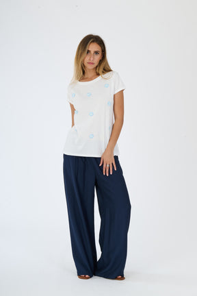 Outfit di stile quotidiano e confortevole: maglietta bianca a pois e pantaloni larghi scuri, esibizione di uno stile fashion rilassato