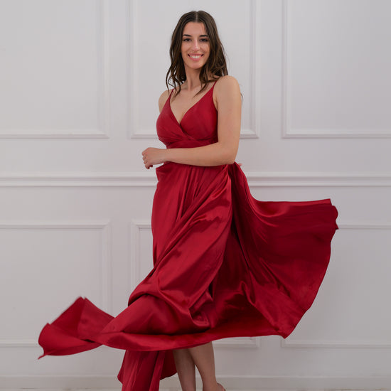 Abito vino plissé e pose stilosa, lago e case sulle colline sullo sfondo