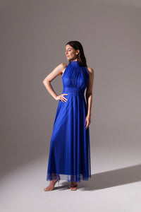 Donna in abito blu scuro fluido, colletto alto, posa con bracci alzati per esibire il vestito